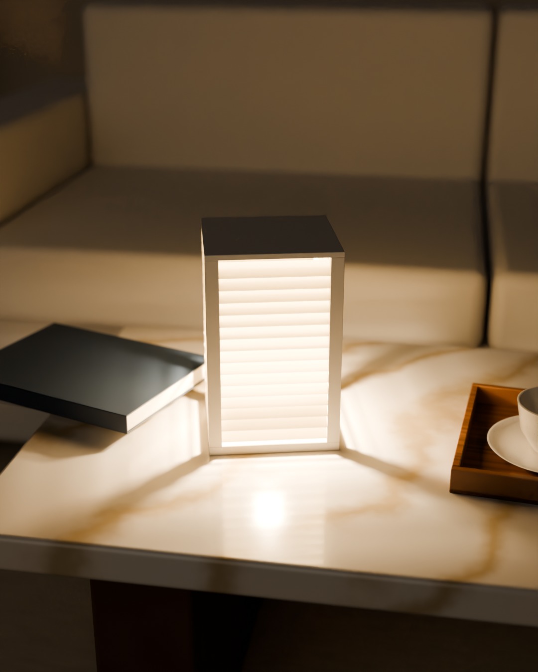 BIDAI table lamp in bone white, switched on, on a coffee table