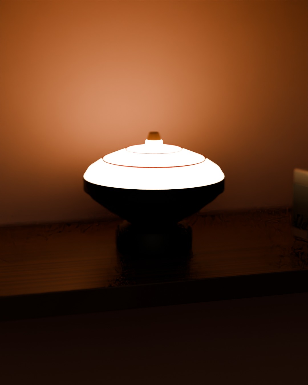 GASING cordless lamp in red, steel grey and wood, switched on, on a bookshelf