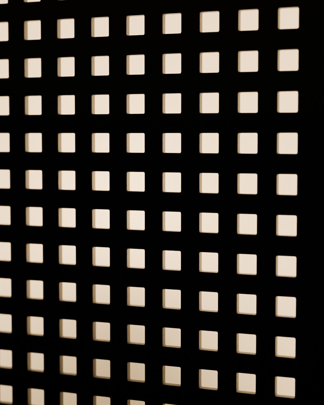 Close-up of the MATRIX table lamp in graphite, switched on, on a bookshelf, the dot-matrix grid