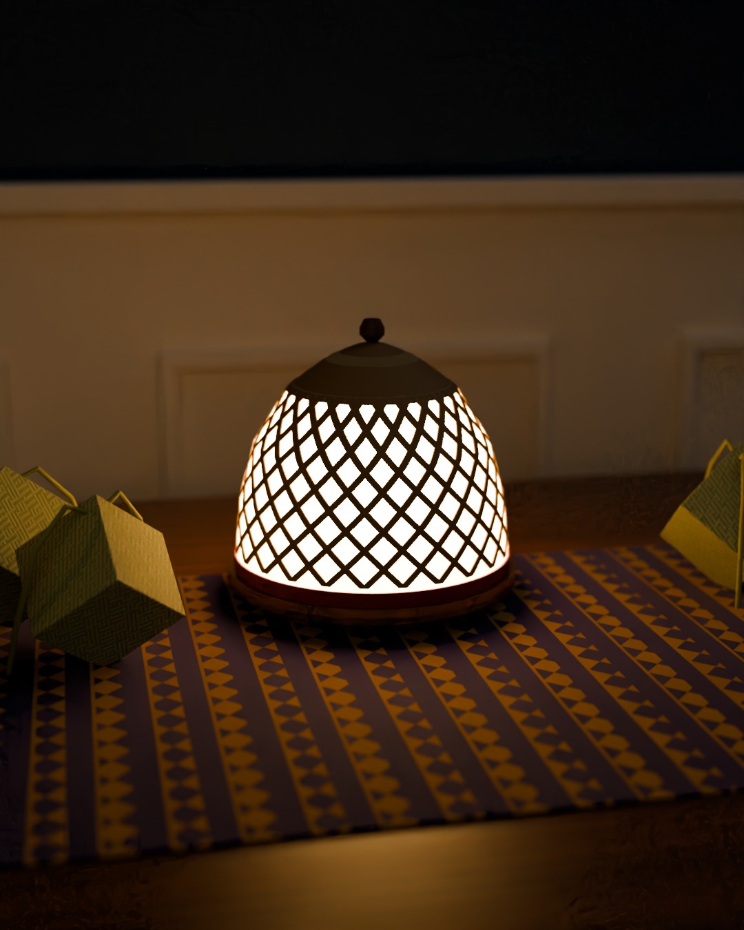 TUDUNG table lamp in bone, red and brass, switched on, in a Hari Raya living room